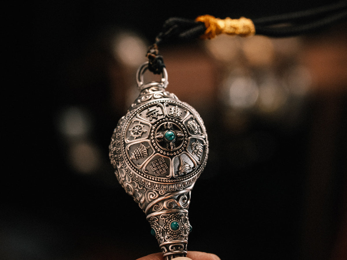 Hand-carved sterling silver Dharma Conch pendant carrying the Eight Auspicious Symbols, beside Tibetan prayer beads