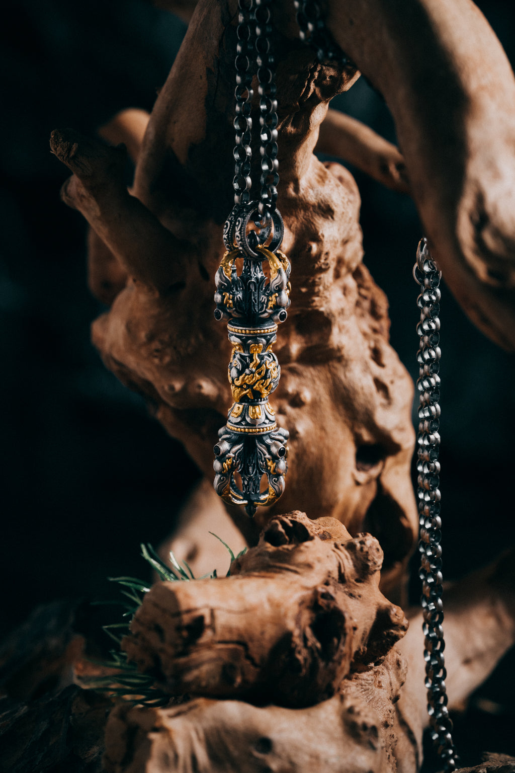 Fire-gilded garuda vajra pendant laid on driftwood, beaded collars and flame scrollwork