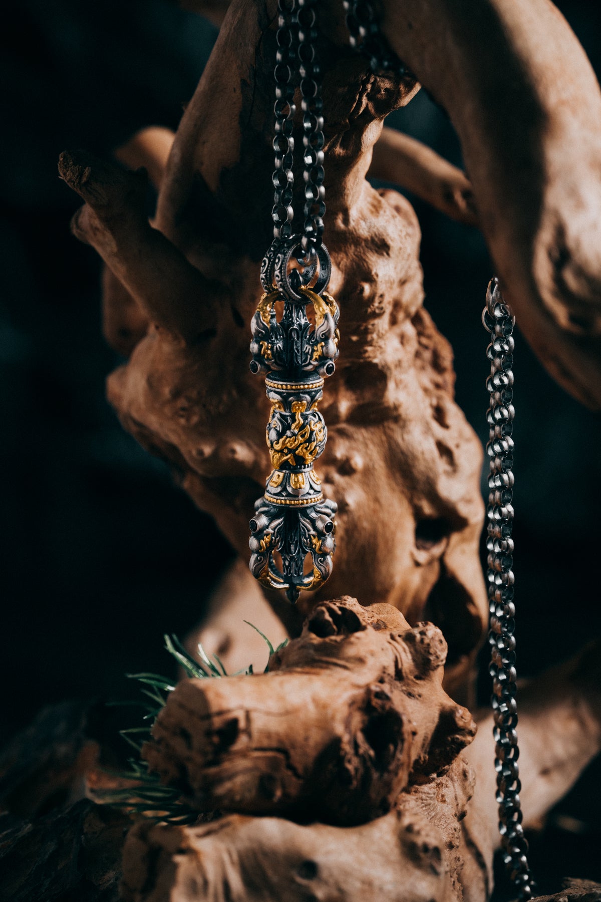 Fire-gilded garuda vajra pendant laid on driftwood, beaded collars and flame scrollwork