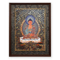 Amitabha Buddha black and gold thangka with blue crystal halo, framed in Ink & Gold silk brocade, on a white background