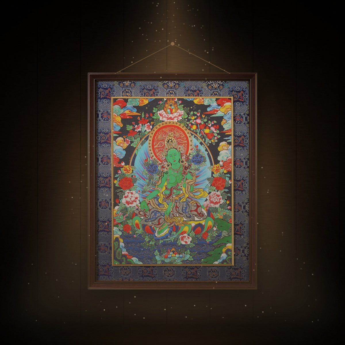 Green Tara night-blue thangka hanging in a room under warm light
