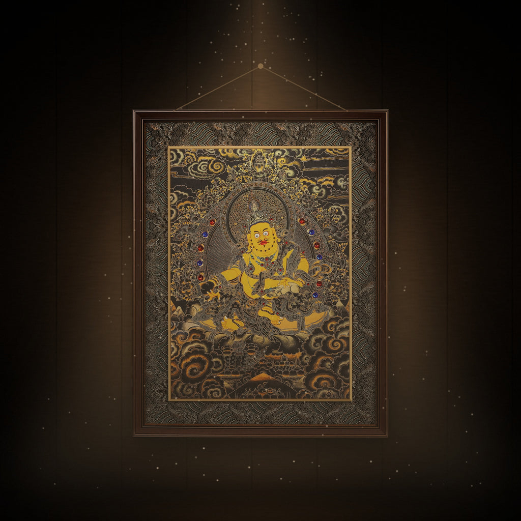 Yellow Jambhala black and gold thangka hanging in a room under warm light