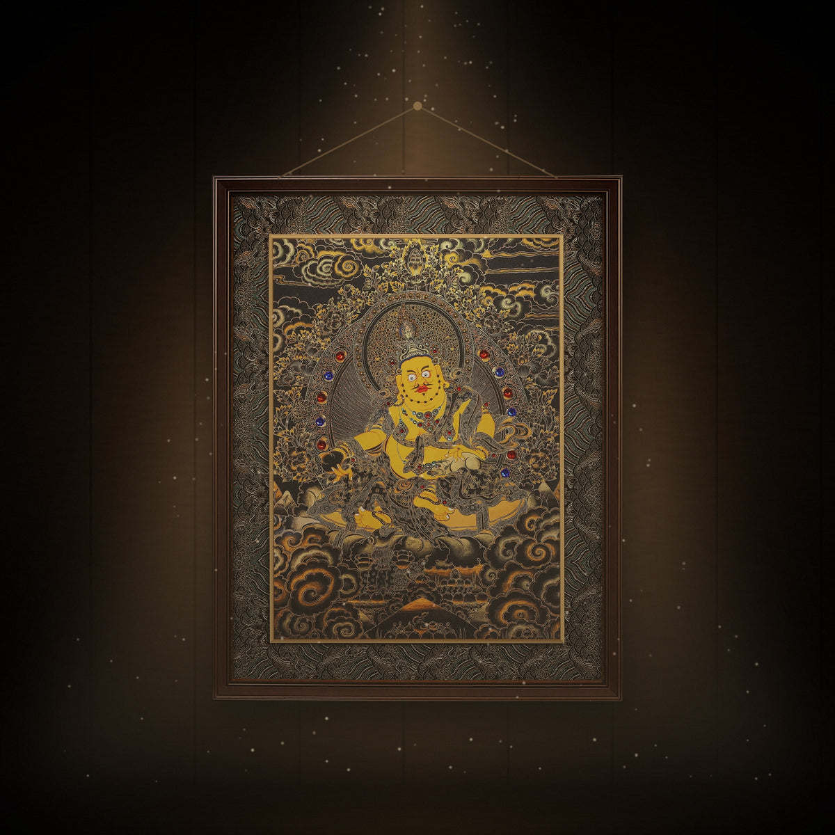 Yellow Jambhala black and gold thangka hanging in a room under warm light